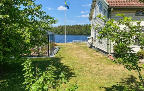 a house with a yard next to a body of water at Nice Home In Hjältevad With Sauna in Hjältevad