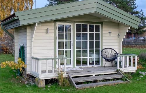 a small house with a porch and a chair on a deck at Nice Home In Hjältevad With Sauna in Hjältevad
