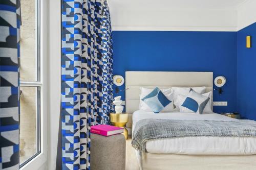 a blue bedroom with a bed and a window at Hotel Elysees Opera in Paris