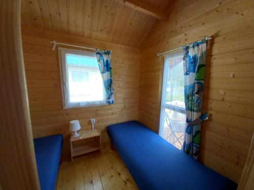 a small room with a blue bed and a window at Domki Żeglarz Ustronie Morskie in Ustronie Morskie
