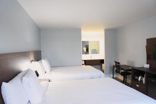 a hotel room with two beds and a desk at Florence Inn and Suites in Florence