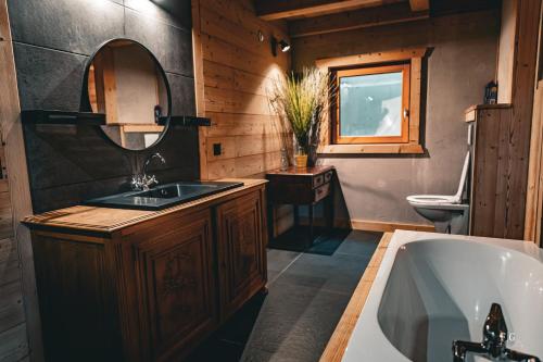 ein Badezimmer mit einem Waschbecken, einer Badewanne und einem Spiegel in der Unterkunft Le Chalet de Vincent in Cordon
