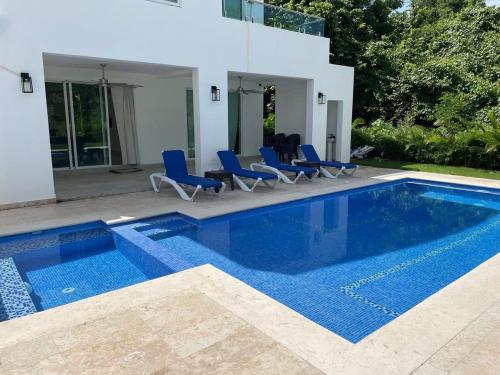 a swimming pool with blue chairs next to a house at Luxury place playa nueva romana in San Pedro de Macorís