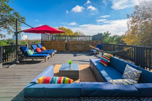 a deck with blue couches and a red umbrella at Breathtaking Roof Pool Views, Gameroom, Firepit in San Antonio
