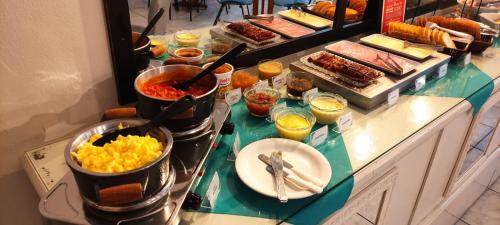 un buffet con huevos y otros alimentos en un mostrador en Hotel LF By Feliciano, en Barracão