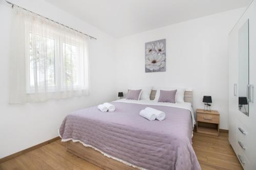 a white bedroom with a large bed with towels on it at Villa Natura Piedra in Slivno