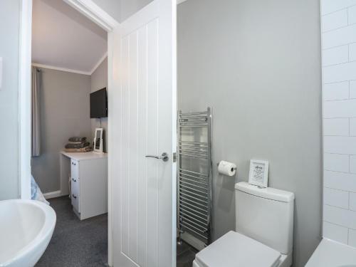 a white bathroom with a toilet and a sink at Lake View Lodge in Tallington