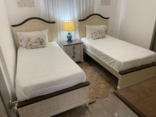 2 camas en un dormitorio con una lámpara en una mesa en Nuevo Apto in Juan Dolio en Guayacanes