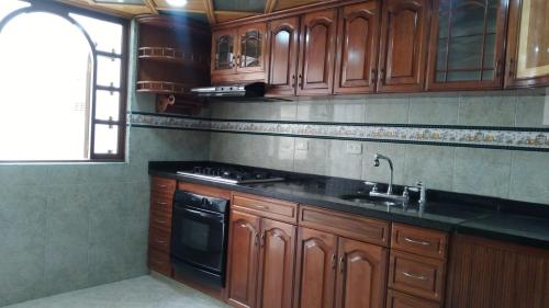 cocina con armarios de madera, fregadero y fogones en cálida, acogedora habitación cerca a Unicentro de occidente, en Bogotá