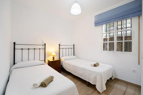 2 Betten in einem Zimmer mit Fenster in der Unterkunft Apartamento Ribera del Marisco in El Puerto de Santa María