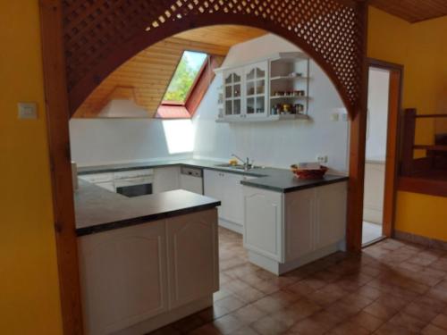 una cocina con armarios blancos y un arco en Saci Lak, en Gyenesdiás