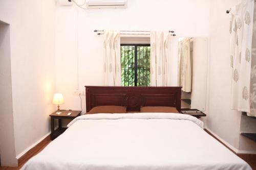 a white bedroom with a bed and a window at 4BHK Private Pool villa in North Goa and Kayaking nearby!! in Moira