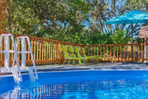una piscina con 2 sillas de césped y una sombrilla en Texas Vacation Home, Game Room & Pool By Sixflags, en San Antonio