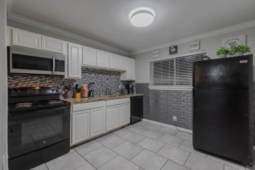 a kitchen with white cabinets and a black refrigerator at Beautiful Apartment At The Botanical Gardens #1 in San Antonio