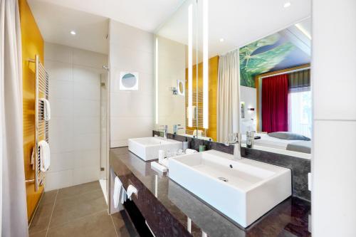 a bathroom with two sinks and a large mirror at Kaisergarten Hotel Deidesheim in Deidesheim