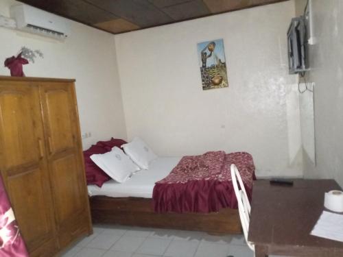 a small bedroom with a bed and a table at Hôtel Le Quilombo in Garoua