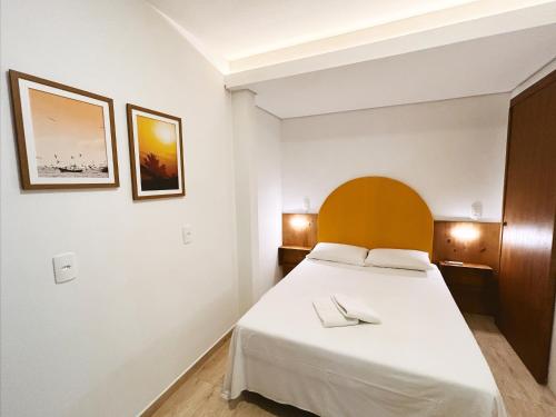 1 dormitorio con cama blanca y cabecero de madera en Babitonga Hostel - 100m da Prainha en São Francisco do Sul