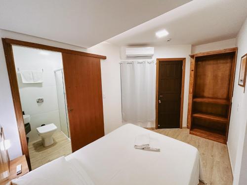 a bathroom with a white bed and a toilet at Babitonga Hostel - 100m da Prainha in São Francisco do Sul