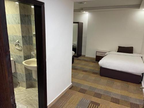 um quarto com uma cama e uma casa de banho com um lavatório em Skylight apartments em Amã