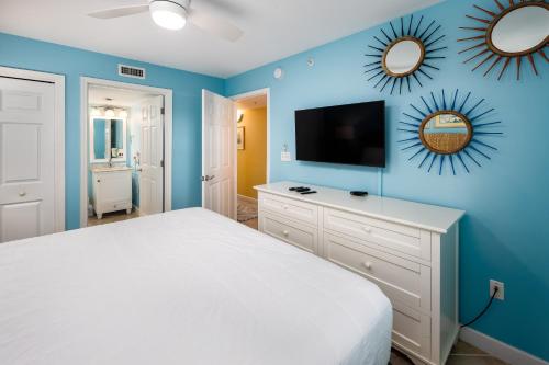 een slaapkamer met een wit bed en blauwe muren bij Pelican Isle 406 in Fort Walton Beach