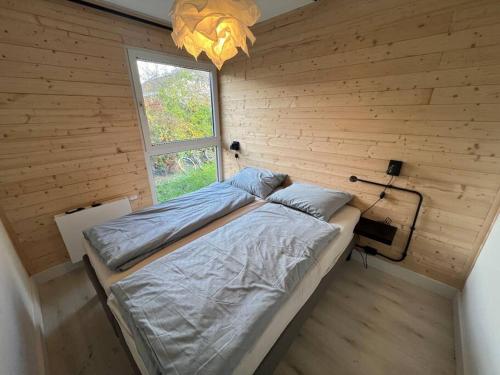 1 dormitorio con 1 cama grande en una pared de madera en Moderne bungalow voor 6 personen, en Julianadorp