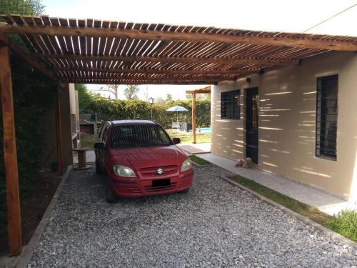 un coche rojo aparcado bajo una pérgola de madera en Casa ROMA en San Rafael