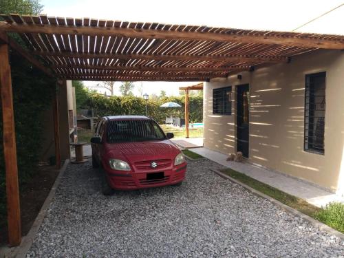 un coche rojo aparcado bajo una pérgola de madera en Casa ROMA, en San Rafael