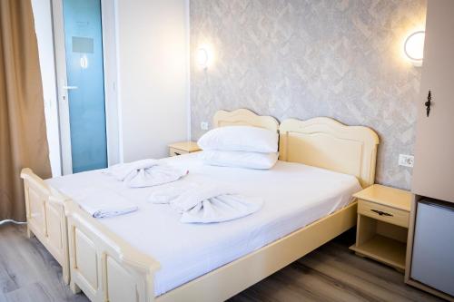 Schlafzimmer mit einem Bett mit weißer Bettwäsche und Kissen in der Unterkunft Club Dunarea in Eforie Nord