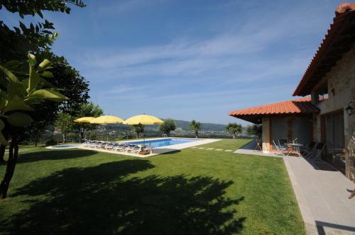 a garden with a swimming pool and two yellow umbrellas at Villa 251 in Barcelos