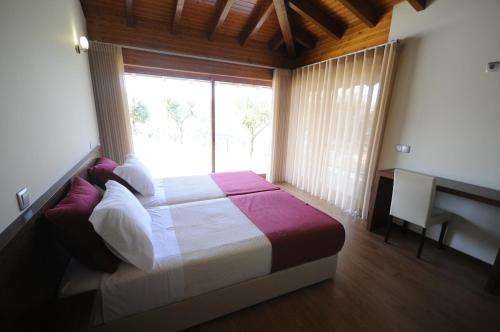 a bedroom with a bed with a window and a desk at Villa 251 in Barcelos
