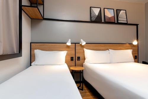 two beds sitting next to each other in a room at ibis Porto Alegre Aeroporto in Porto Alegre