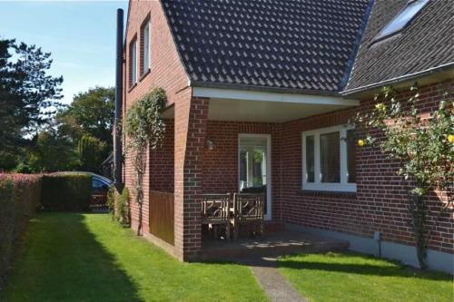 a brick house with a table and chairs in the yard at Ferienhaus VOGELKIEKER in Midlum