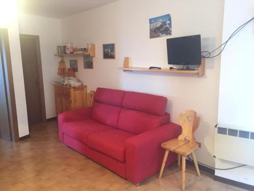 - un canapé rouge dans le salon doté d'une télévision dans l'établissement Aprica Sports and Relax, à Villa di Tirano