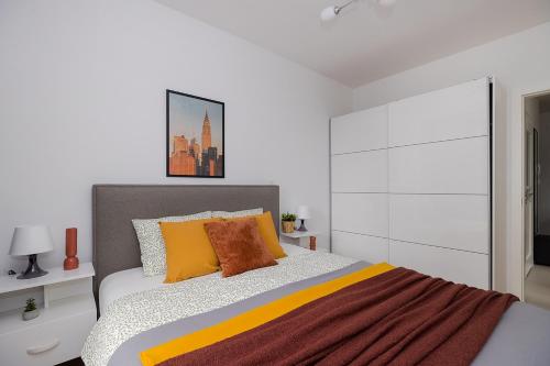 1 dormitorio con 1 cama con almohadas de color naranja y amarillo en SuperApart Przyokopowa 35, en Varsovia