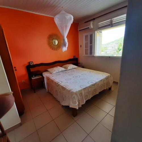 a bedroom with a bed with an orange wall at La villa du manguier in Le Vauclin