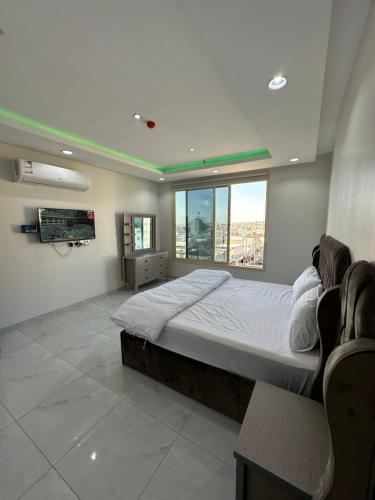 sypialnia z dużym łóżkiem i dużym oknem w obiekcie برج موجان السكني التجاري w mieście Chamis Muszajt