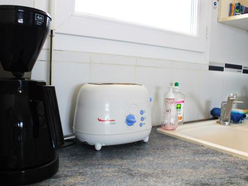 Un grille-pain est installé sur un comptoir de cuisine à côté d'un évier. dans l'établissement Spacieux T4 climatisé avec parking au cœur de Rochelongue - FR-1-607-29, au Cap d'Agde