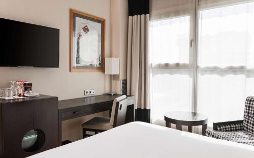 a hotel room with a bed and a desk at NH Valencia Center in Valencia