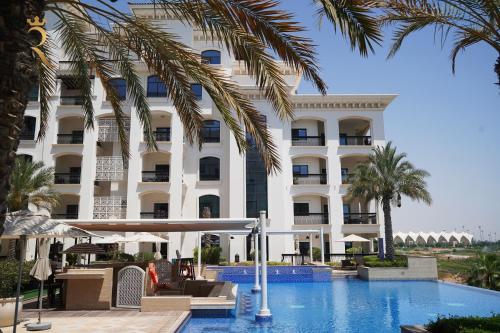 a hotel with a swimming pool in front of a building at Modern 1BR Stay - Yas Natura Chic Luxe Retreat in Abu Dhabi