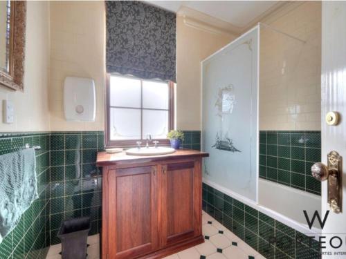 a green tiled bathroom with a sink and a shower at A peaceful room in Northbridge with free parking in Perth