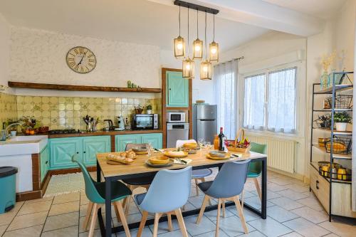 uma cozinha com armários azuis e uma mesa com cadeiras em Maison sur la route du Cognac em Saint-Même-les-Carrières