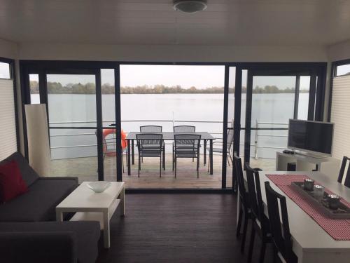 ein Wohnzimmer mit einem Tisch und Blick auf das Wasser in der Unterkunft FLOATING 44 Xanten - Haustiere möglich in Xanten