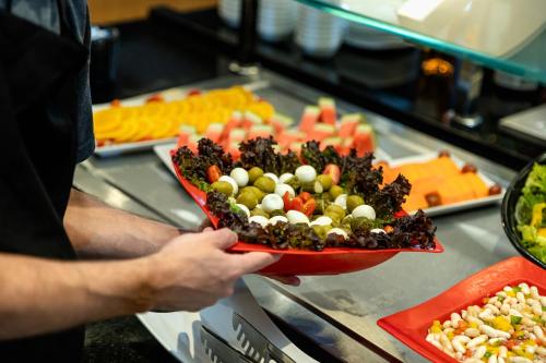 a person holding a plate of food on a buffet at ibis Porto Alegre Aeroporto in Porto Alegre