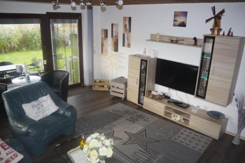 a living room with a tv and a chair at Ferienhaus Mitteldeich in Butjadingen