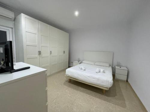 een witte slaapkamer met een bed en een televisie bij Apartamento Almogávares in Córdoba