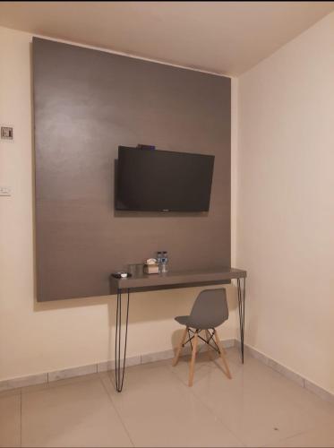 a desk with a television on a wall with a chair at Zester Hotel Sidoarjo in Sidoarjo