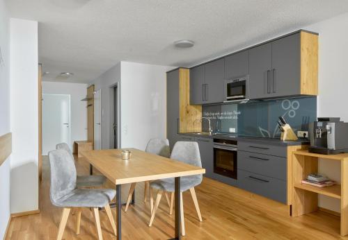 a kitchen and dining room with a wooden table and chairs at Zapfig Living Arlberg in Wald am Arlberg