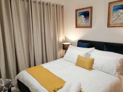Un dormitorio con una cama blanca con una manta amarilla. en The Blyde Lagoon, Pretoria, en Pretoria