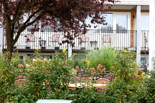 a garden with a wooden table and chairs and plants at Hotel Restaurant Eeserhof in Ees