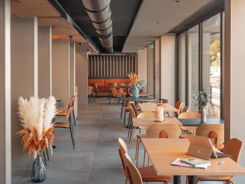 un restaurant avec des tables, des chaises et des fenêtres dans l'établissement Novotel Paris Val de Fontenay, à Fontenay-sous-Bois